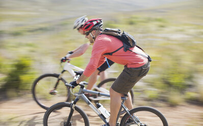 Blurred view of mountain bikers on dirt path - CAIF04111