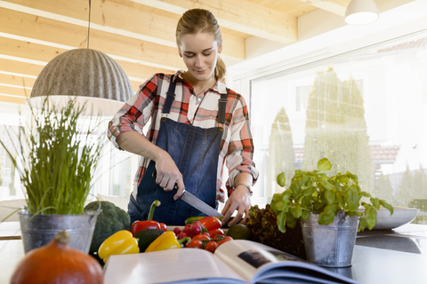 Pregnant woman in kitchen at home cutting cucumber stock photo