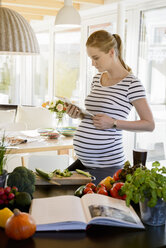 Pregnant woman in kitchen at home using tablet - BMOF00010