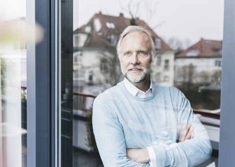 Porträt eines reifen Mannes, der aus einer Glastür schaut, lizenzfreies Stockfoto