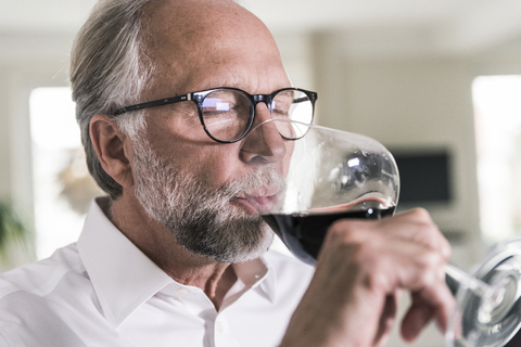 Porträt eines reifen Mannes, der ein Glas Rotwein trinkt, lizenzfreies Stockfoto