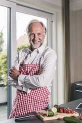 Portrait of smiling mature man with apron in his kitchen - UUF12974