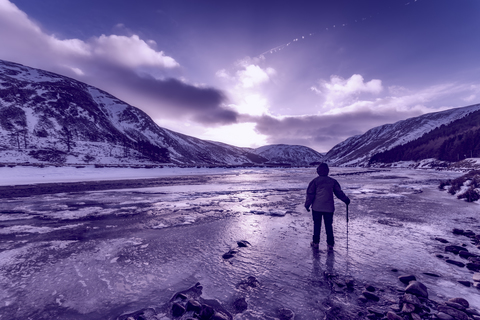 Vereinigtes Königreich, Schottland, Highlands, Wanderin steht am vereisten Flussufer, lizenzfreies Stockfoto