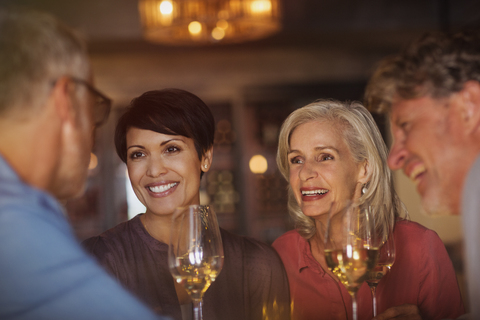 Paare trinken Weißwein und unterhalten sich an der Bar, lizenzfreies Stockfoto