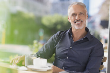 Portrait smiling man drinking coffee at urban sidewalk cafe - HOXF00026