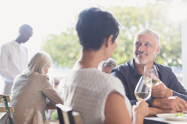 Ein Paar unterhält sich und trinkt Weißwein am Tisch eines Restaurants im Freien - HOXF00028