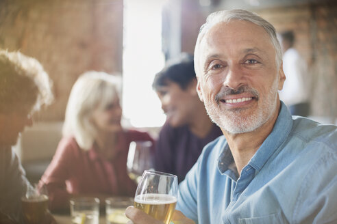 Porträt eines selbstbewussten Mannes, der mit Freunden am Restauranttisch Weißwein trinkt - HOXF00030