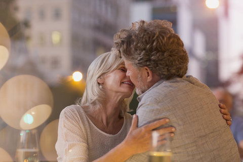 Zärtliches älteres Paar küsst sich in einem städtischen Straßencafé, lizenzfreies Stockfoto