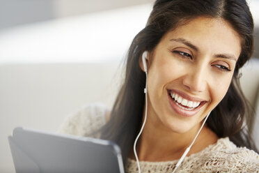 Close up smiling woman using digital tablet with headphones - HOXF00054