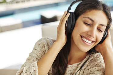 Smiling woman listening to music with headphones and eyes closed - HOXF00063
