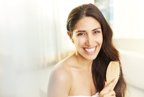 Porträt lächelnde brünette Frau beim Bürsten der Haare - HOXF00073