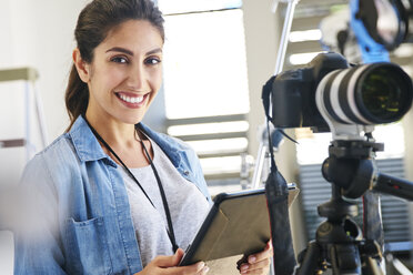 Porträt lächelnde Fotografin mit digitalem Tablet hinter der Kamera im Studio - HOXF00095