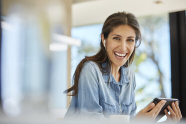 Porträt einer begeisterten Frau mit digitalem Tablet und Kopfhörern - HOXF00098