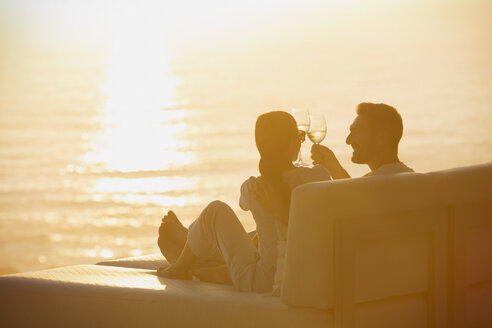 Silhouette Paar Toasting Weingläser auf Liegestuhl mit Sonnenuntergang Blick aufs Meer - HOXF00134