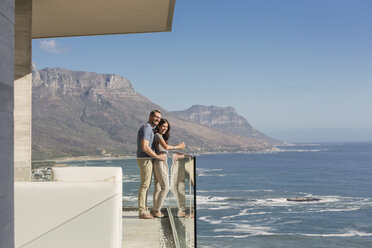 Couple looking at sunny ocean view from luxury balcony - HOXF00135