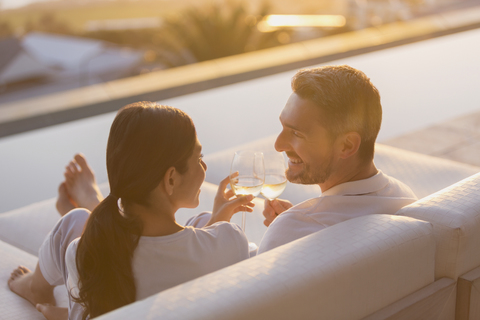 Couple relaxing toasting white wine glasses on chaise lounge on luxury patio stock photo