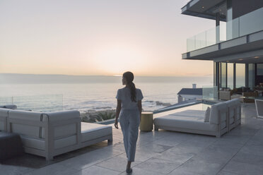 Woman walking on luxury home showcase exterior patio at sunset - HOXF00157