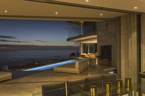 Beleuchtete Musterterrasse mit Pool und Blick aufs Meer in der Dämmerung, lizenzfreies Stockfoto