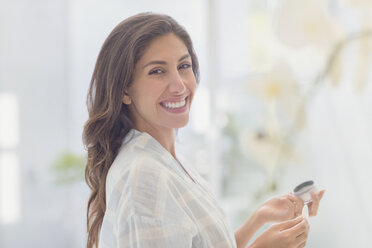 Portrait smiling brunette woman applying makeup - HOXF00176