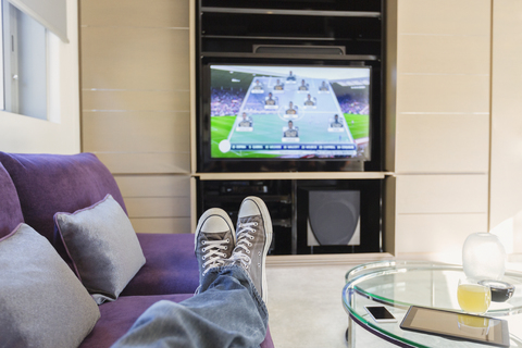Personal perspective man with feet up watching soccer game on TV in living room stock photo