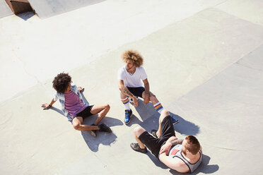 Draufsicht auf männliche Freunde, die im sonnigen Skatepark abhängen - CAIF04196