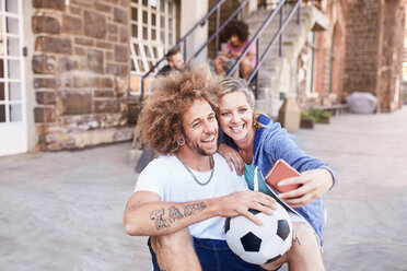 Couple with soccer ball taking selfie with camera phone - CAIF04199