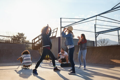 Freunde, die sich im sonnigen Skatepark die Hände reichen - CAIF04200