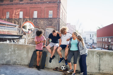 Freunde mit Skateboards hängen an einer städtischen Sommerwand ab - CAIF04202