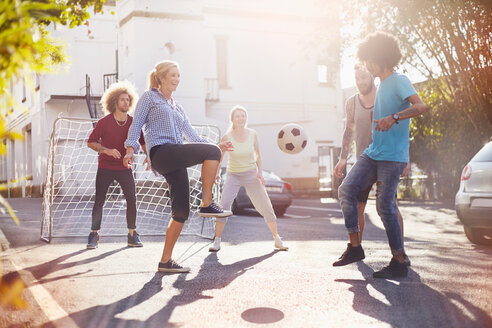 Freunde spielen Fußball in sonnigen Sommer Straße - CAIF04203