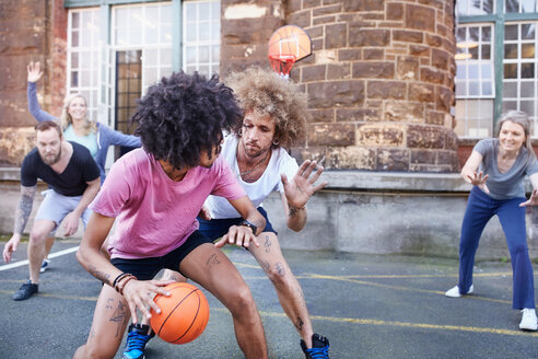 Freunde spielen Basketball auf einem städtischen Basketballplatz - CAIF04210