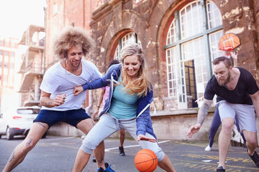 Friends playing basketball on urban basketball court - CAIF04212