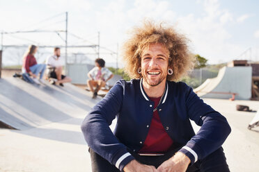 Porträt selbstbewusster junger Mann mit Afro im sonnigen Skatepark - CAIF04217