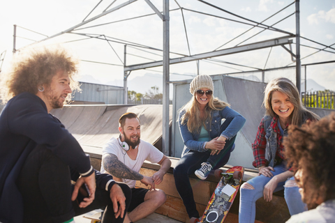 Freunde hängen ab und unterhalten sich im sonnigen Skatepark, lizenzfreies Stockfoto