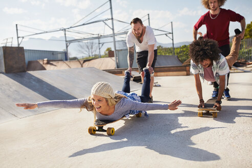 Verspielte Freunde auf Skateboards im sonnigen Skatepark - CAIF04230
