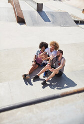 Draufsicht auf männliche Freunde, die ein Selfie mit einem Fotohandy in einem sonnigen Skatepark machen - CAIF04236