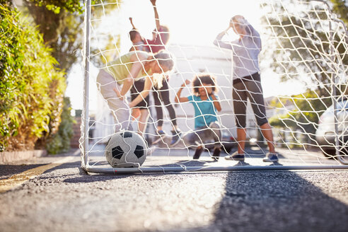 Freunde spielen Fußball auf einer sonnigen städtischen Sommerstraße - CAIF04242