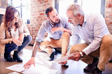 Business people discussing paperwork and brainstorming at office floor - CAIF04271