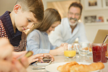 Junge benutzt Mobiltelefon am Frühstückstisch - CAIF04292