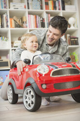 Vater schiebt Babysohn in Spielzeugauto - CAIF04294