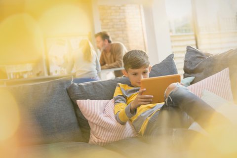 Junge mit digitalem Tablet auf dem Sofa, lizenzfreies Stockfoto