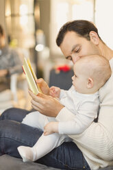 Father reading book to cute baby son - CAIF04310