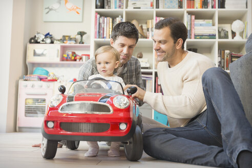Männliche schwule Eltern und ihr kleiner Sohn spielen mit einem Spielzeugauto - CAIF04312