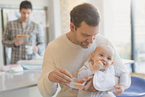 Vater füttert seinen kleinen Sohn mit Möhren, lizenzfreies Stockfoto