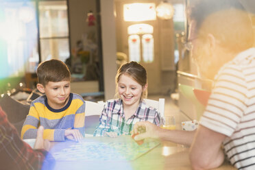 Vater und Kinder spielen ein Brettspiel am Tisch - CAIF04333