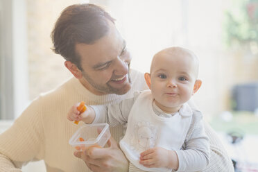 Porträt lächelnd, süßes Baby Sohn und Vater essen Karotten - CAIF04336