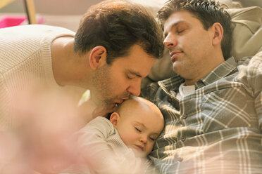 Affectionate male gay parents kissing sleeping baby son - CAIF04350