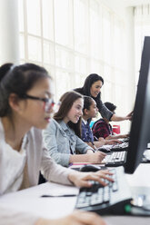 Lehrerin hilft Schülern bei der Arbeit an Computern im Computerraum - CAIF04356