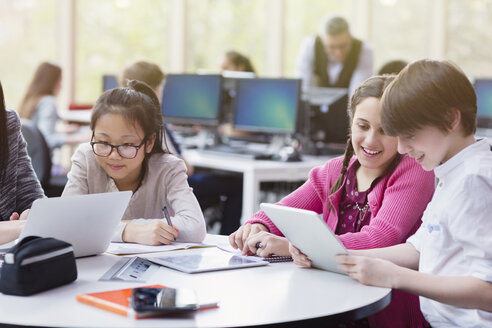 Schüler benutzen Tablet und Laptop in der Bibliothek - CAIF04369