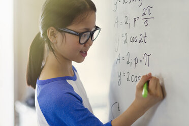 Porträt einer lächelnden, selbstbewussten Studentin, die im Klassenzimmer Physikgleichungen am Whiteboard löst - CAIF04371