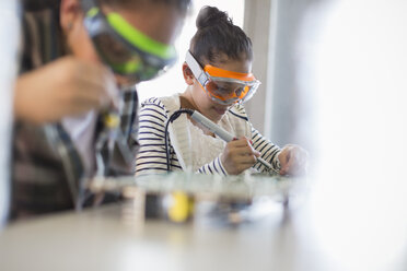 Focused girl students soldering circuit boards in classroom - CAIF04380